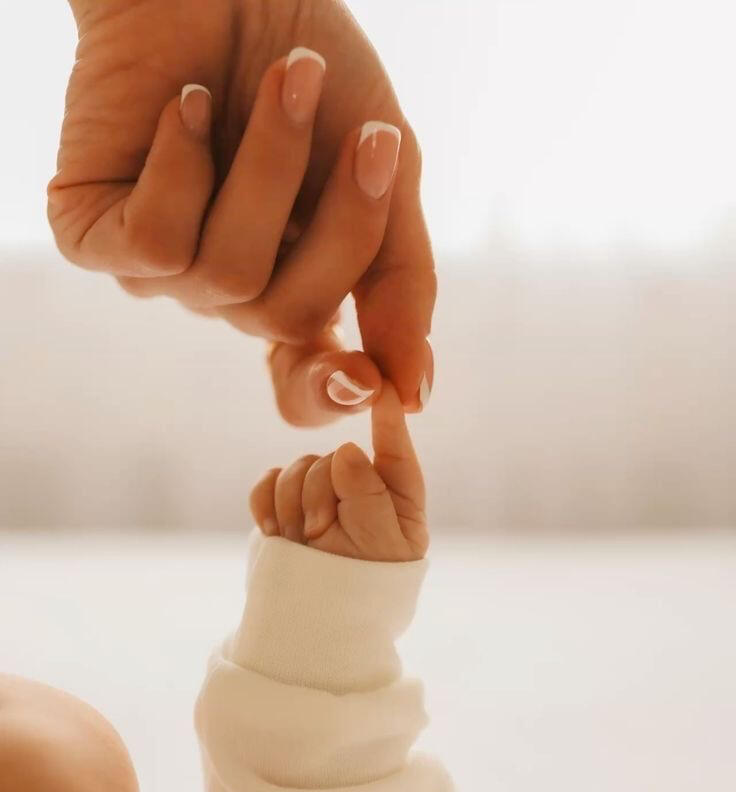 Mains maman bébé Main avec French manucure, tient doigt de bébé